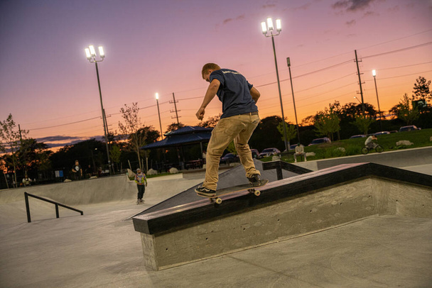 Detroit, Michigan, USA - 9.04.2019: Skaters and BMX bikers practice tricks in Detroit sunset - Photo, image