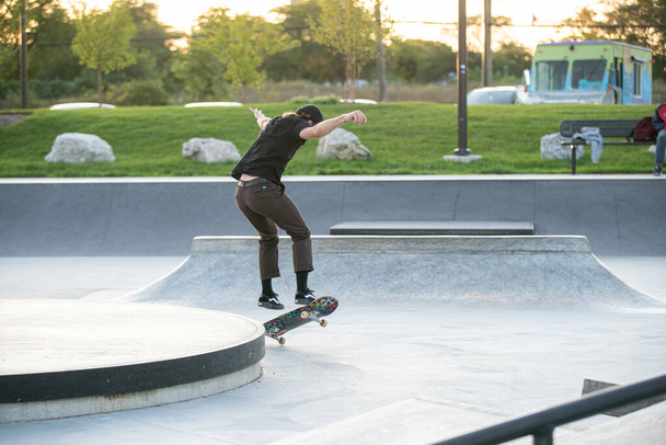 Detroit, Michigan, USA - 10.07.2019: Skater und Biker üben Tricks bei Sonnenuntergang im Skatepark in Detroit - Foto, Bild