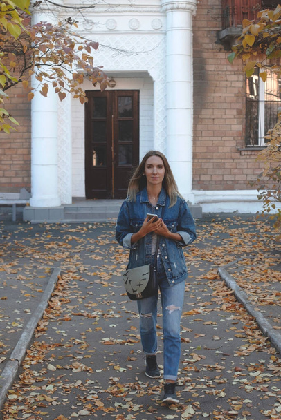 Una ragazza vestita completamente in denim total look passeggia in autunno in città. - Foto, immagini