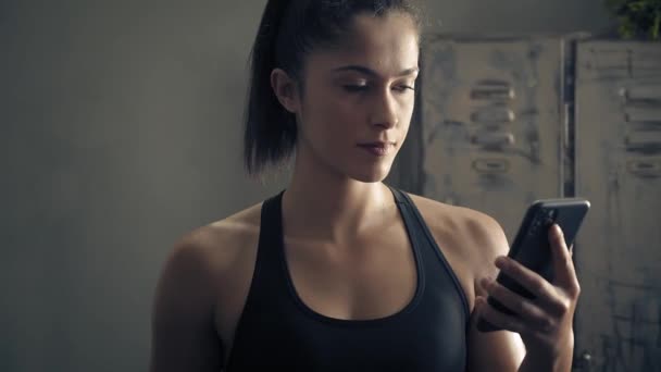 woman using smart phone with personal trainer workout app at home. Woman preparing for workout using fitness app. Close orbit shot.Woman using mobile phone while resting during fitness training  - Filmmaterial, Video