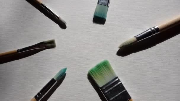 Gebruikte penselen voor het schilderen op wit getextureerd papier. Bovenaanzicht - Video
