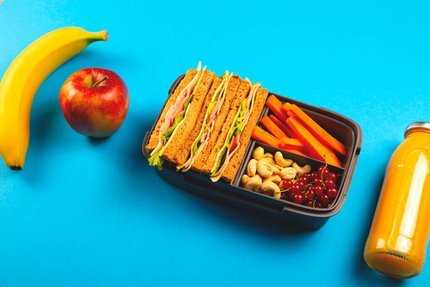 Zdravé školní oběd v pohodlném kontejneru na jasně modrém pozadí. - Fotografie, Obrázek