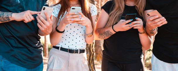 Tinédzser barátok csoportja mobiltelefonnal - Emberek, akik jól érzik magukat a technológiai trendekkel - Ifjúsági életmód, technológia, millenniumi generáció és társadalmi trend koncepció - Fő hangsúly a középkézen - Fotó, kép
