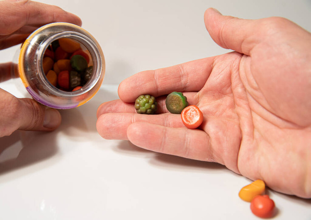 vitaminas gostosas, comprimidos coloridos nas mãos do homem  - Foto, Imagem