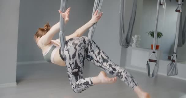 Kobieta podnosi ćwiczenia na hamaku w klasie jogi muchy, elastyczna kobieta robi gimnastykę akrobatyczną i plastyczną, jogę i rozciąganie, 4k 60p Prores 422 10 bit - Materiał filmowy, wideo