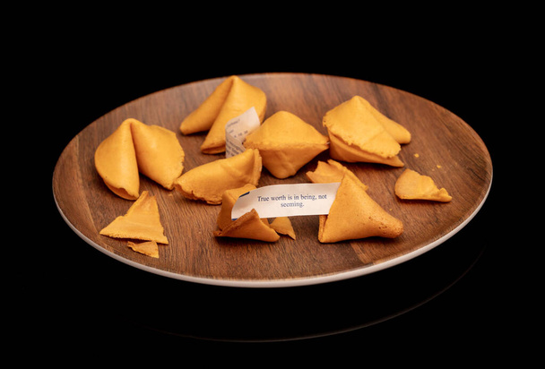 Crisp and sugary fortune cookies on wooden brown plate isolated on black - Photo, Image
