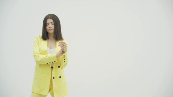Pretentious brunette woman in yellow formal suit clapping, and looking annoyed over white background - Video