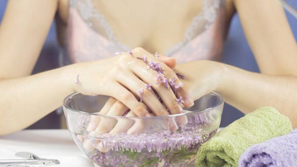 Hände einer Frau in einer Badewanne mit Blumen. Maniküre, Nagelpflege. Sinnlichkeit, Hautpflege, feminin, Salon, Waschen, Wohlstand, Therapie, Kosmetik, Behandlung, Entspannung, Tagesspa, Aromatherapie - Foto, Bild