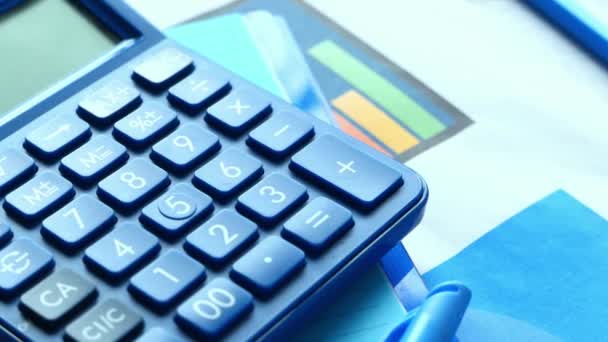 Primer plano de la calculadora azul y gráfico financiero en la tabla. - Metraje, vídeo