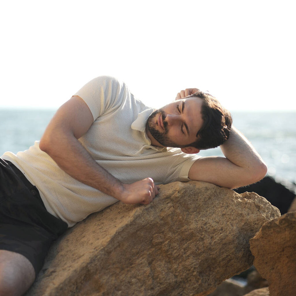 Young stylish resting man outdoor portrait near the sea - Фото, изображение