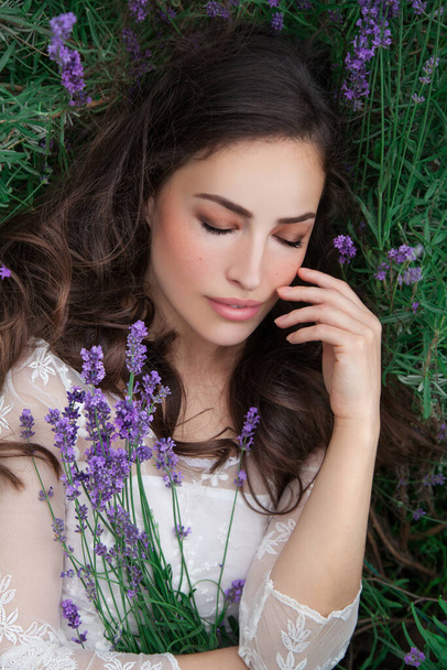 pretty young woman lying in lavender field, outdoor beauty portrait - Fotó, kép