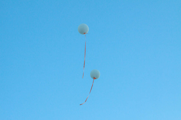 Grands ballons d'hélium bleu avec rubans orange dans le ciel bleu sans nuages. Concept idée de mariage, arrière-plan - Photo, image
