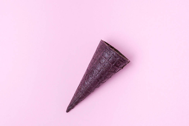 Corne de gaufre violette remplie de fromage cottage en glaçure chocolat sur fond rose, couchée à plat, en diagonale. Dessert rafraîchissant à la gaufre, concept d'idée, vue de dessus, gros plan - Photo, image