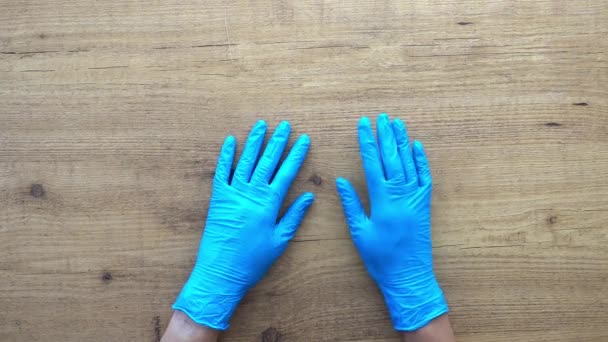 Las manos de mujer con guantes de látex azul golpeando ansiosamente sus dedos sobre la mesa. Esperando concepto. Vista de arriba hacia abajo
 - Imágenes, Vídeo