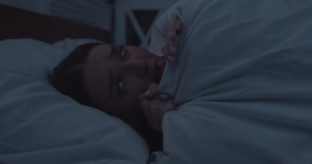 Fille inquiète couchée au lit, couvrant le visage avec une couverture - Séquence, vidéo