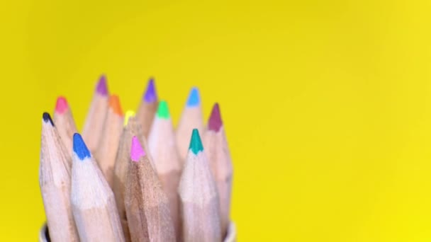 Sluitingsset van gekleurde houten potloden in verschillende kleuren draaiend op gele achtergrond. Geïsoleerd object met kopieerruimte. Terug naar schoolconcept. - Video