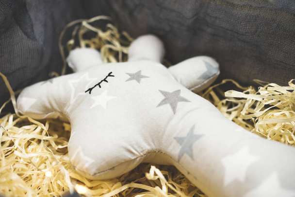 Саморобна м'яка іграшка жирафа лежить на мішурі в подарунковій коробці. Ручне шиття сірого жирафа з зірками. Близько. Вибірковий фокус
. - Фото, зображення