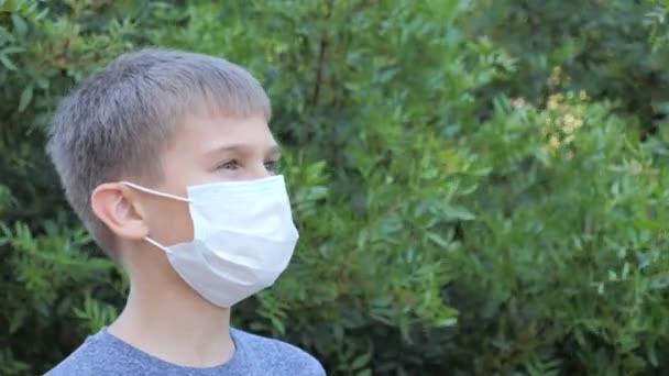 少年は医療用のマスクを脱ぎ、深く息をして微笑む。屋外に立って、 covid-19コロノウイルスパンデミック検疫の終わりを楽しむ子供 - 映像、動画