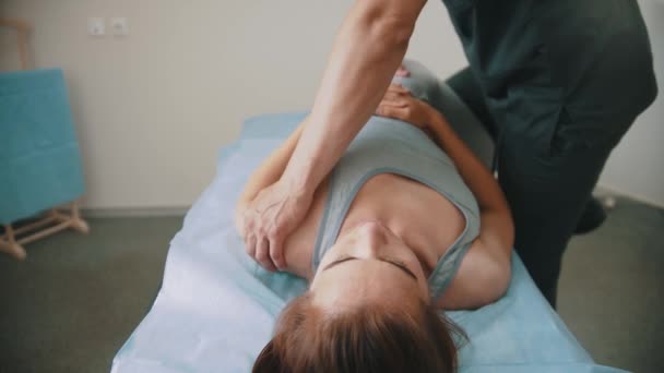 Nainen, jolla on osteopaattinen hoito - makaa sohvalla, kun lääkäri työntää hänen ruumiinsa - Materiaali, video