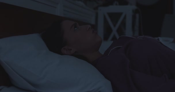 Jonge geïrriteerde vrouw bedekt oren met kussen in bed laat op de avond - Video