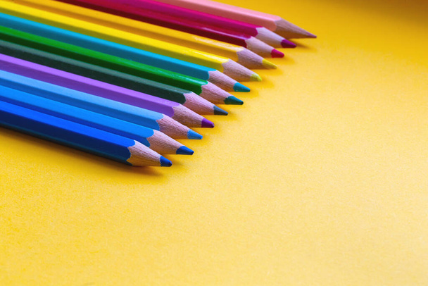 Crayons de couleur en couleurs arc-en-ciel dans une rangée sur fond orange, espace de conception moderne rétro pour le texte - Photo, image