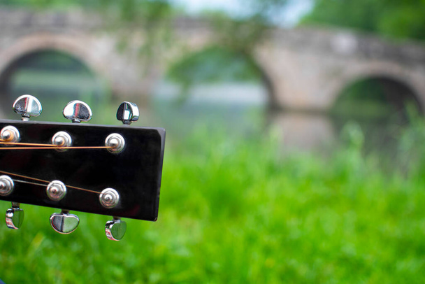 Κοντινό πλάνο της κιθάρας headstock με blured ρωμαϊκή γέφυρα στο παρασκήνιο. Διάσημο τουριστικό μέρος στο Σεράγεβο, Βοσνία - Φωτογραφία, εικόνα