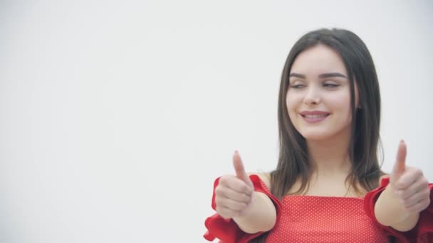 Slowmotin of happy smiling brunette woman showing thumbs up gesture over white background. - Filmagem, Vídeo