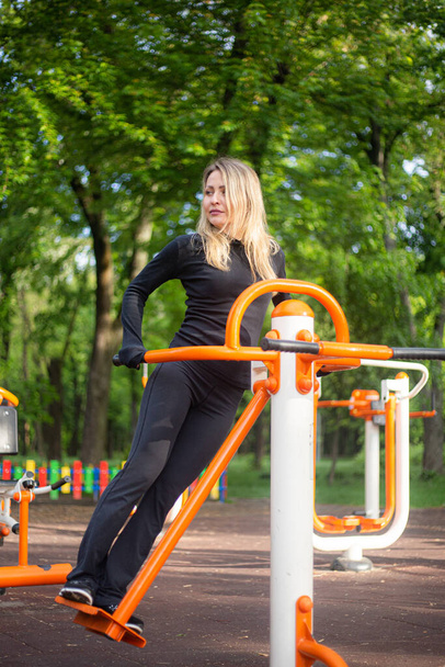 The girl on the summer sports ground does sports exercises on the stepper. Healthy lifestyle. - Foto, Imagen