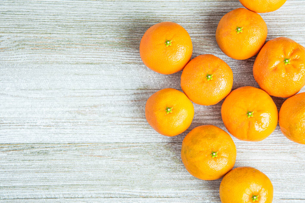 Eine Gruppe frischer Orangen, kunstvoll arrangiert auf einer weiß bemalten Holzplatte. - Foto, Bild