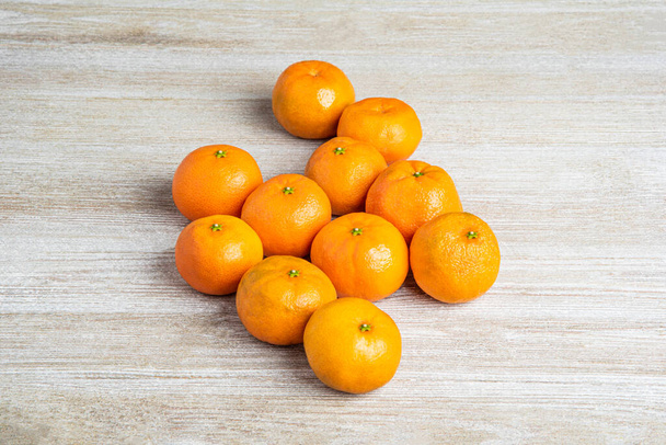 Skupina čerstvých pomerančů umně uspořádaných na bíle natřené dřevěné desce. - Fotografie, Obrázek