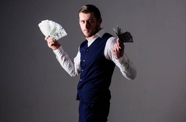 Pensive caucasian young businessman in dark suit holding money - 写真・画像