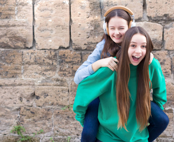 Tini lányok szórakozni a régi tégla fal háttér - Fotó, kép