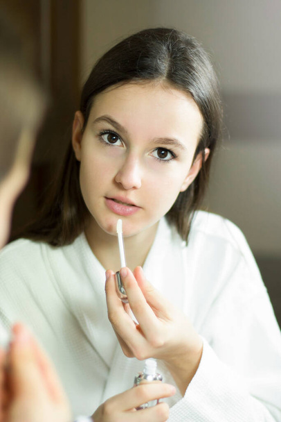 Female beauty, beautiful young woman applying cream on face in bathroom at home. Tennage girl skincare. - Фото, зображення