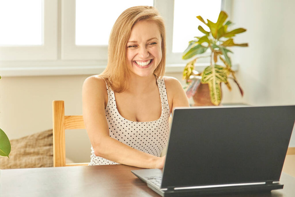 Funny girl professional laughter sitting with a laptop on a home office Desk, positive European woman fun to enjoy sincere emotions laughter study work on a PC. Quarantine, remote work. - Photo, Image