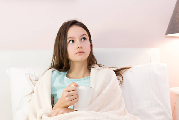 Teen girl lying in bed with a high fever - 写真・画像