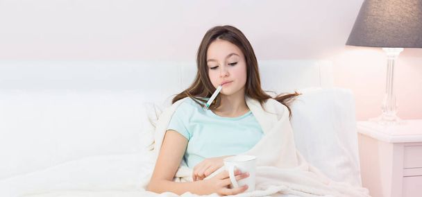 Teen girl lying in bed with a high fever - Foto, afbeelding