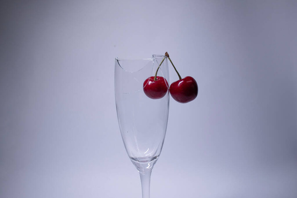 a broken champagne glass with a cherry on it on a white background. Isolated. Copy space. - Fotografie, Obrázek