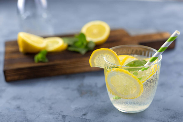 Освежающий летний напиток с лимоном и льдом. Лимонад с эко соломинкой. Расслабляющие безалкогольные или алкогольные коктейли
. - Фото, изображение
