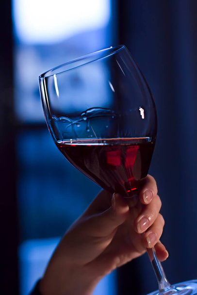 Una copa de vino tinto en mano de mujer
 - Foto, Imagen