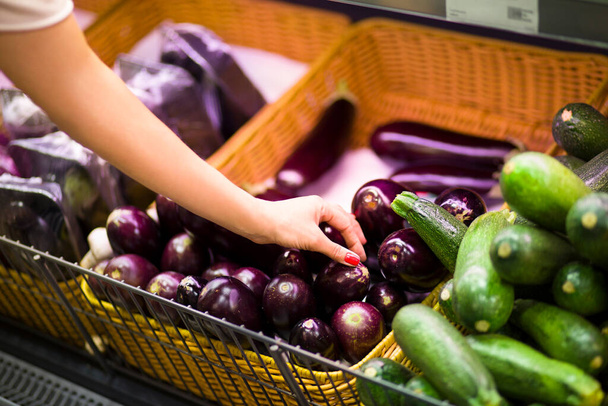 Female hand choosing aubergine in supermarket. Concept of healthy food, bio, vegetarian, diet. - Fotografie, Obrázek