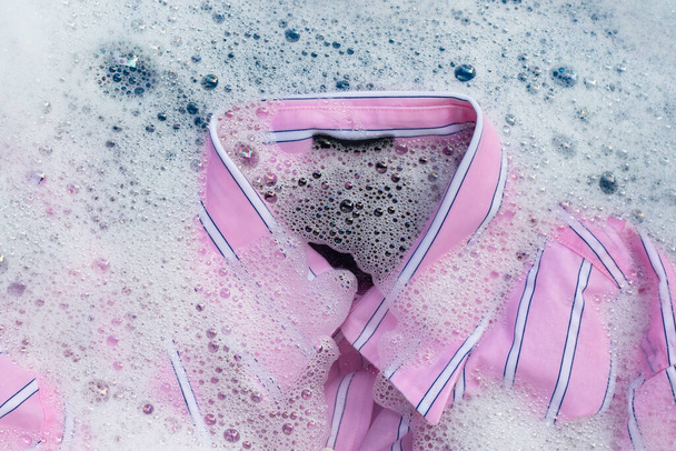 Top view of color clothes soak in powder detergent water dissolution. Laundry concept - Foto, Imagem