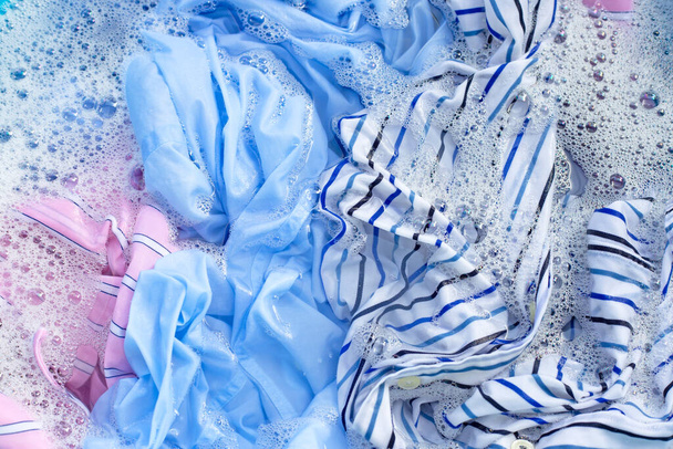 Vista superior de la ropa de color empapar en polvo detergente disolución de agua. Concepto de lavandería
 - Foto, Imagen
