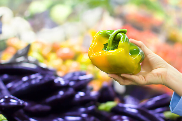 Mano femenina eligiendo pimienta en el supermercado. Concepto de alimentación saludable, bio, vegetariano, dieta
. - Foto, Imagen