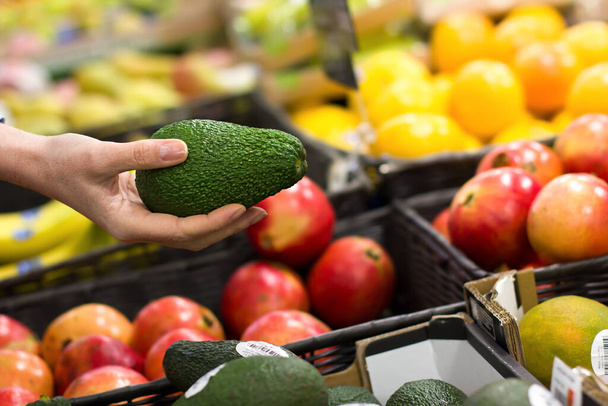 Woman hand choosing avocado at supermarket. Concept of healthy food, bio, vegetarian, diet - Fotoğraf, Görsel