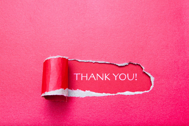 The inscription thank you in the hole in a sheet of red paper on a red background. Layout with torn paper with space for text - Photo, Image