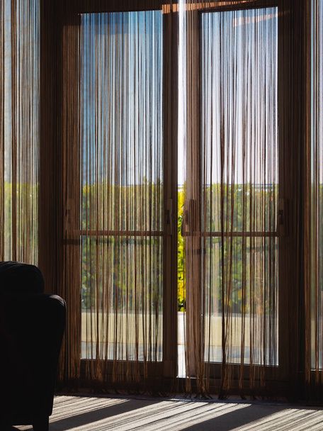 Jaluzili balkonun büyük cam pencereleri biraz aralıktır, güneş ışığı gölge verir. - Fotoğraf, Görsel