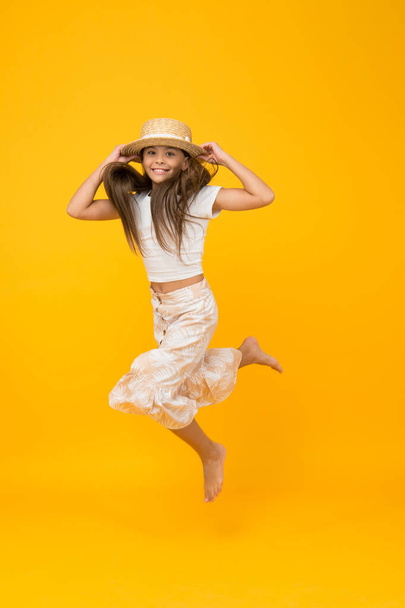 sense of freedom. carefree childhood happiness. small girl wear summer outfit. summer vacation fashion. happy childrens day. having fun on beach party. kid in straw hat. happy barefoot child jump - Valokuva, kuva