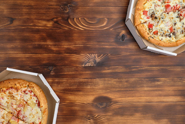 Гавайская пицца и карбонара в картонной упаковке на деревянном фоне с видом сверху и копировальным пространством
. - Фото, изображение