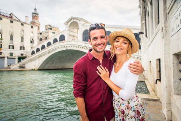 Beatiful young couple having fun while visiting Venice - Tourists travelling in Italy and sightseeing the most relevant landmarks of Venezia - Concepts about lifestyle, travel, tourism - Foto, Imagen