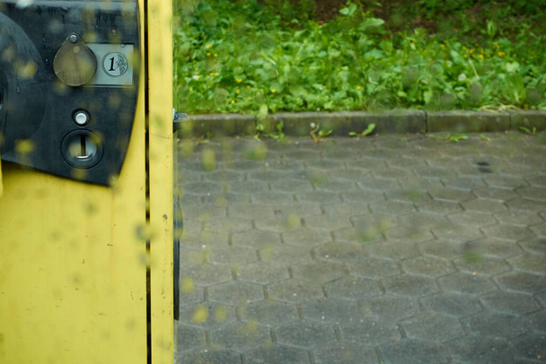 Aspiradora amarilla, en el estacionamiento, con una ranura para monedas de euro, fotografiada a través del cristal de la ventana de lluvia, profundidad de campo, Alemania
. - Foto, imagen
